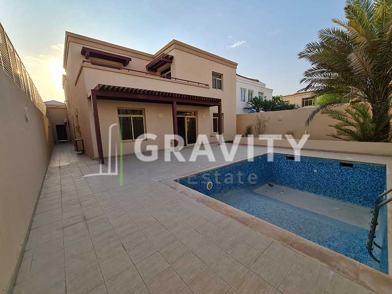 The-backside-of-the-Al-Raha-Golf-Gardens-villa-has-an-empty-swimming-pool-and-an-entrance-to-the-back-of-the-villa