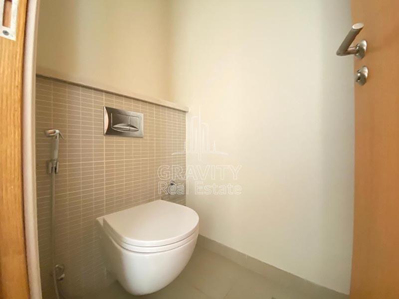 A-small-toilet-with-brown-rectangular-tiles-on-the-walls-in-a-3-bedroom-villa-in-Al-Raha-garden