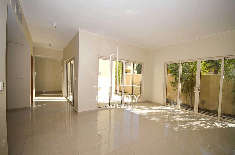 Spacious-white-tiled-living-room-with-the-lobby-to-another-room-and-multiple-windowed-doors-exiting-to-the-backyard-in-a-4-bedroom-Townhouse