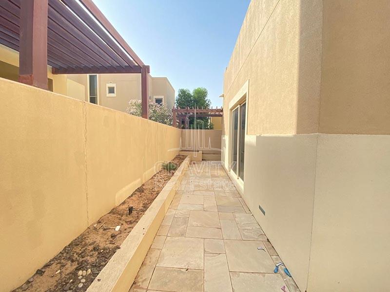 Elognated-pathway-with-stoned-tiled-floorings-on-the-backside-of-a-villa-in-Al-Raha-garden-with-sliding-door-entrance-to-the-villa