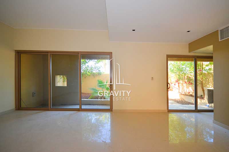 Empty-living-room-having-white-tiles-with-windowed-sliding-doors-that-can-open-to-the-backyard-in-Al-Raha-Garden