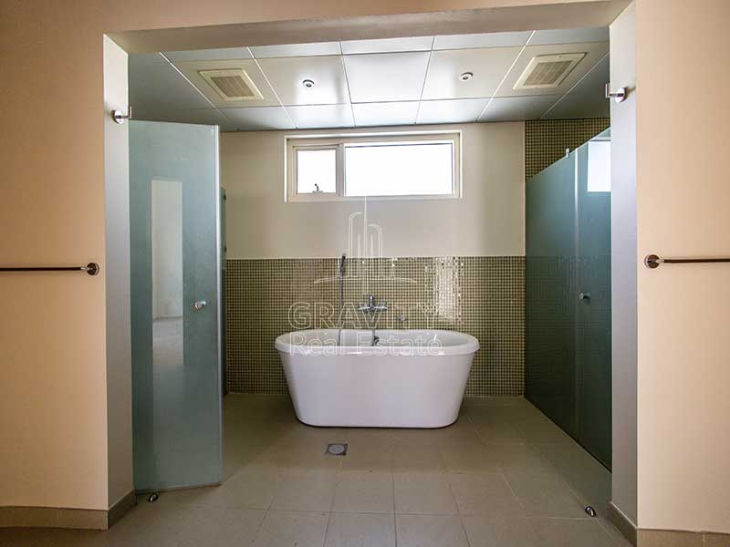 Huge-Toilet-having-2-partitions-for-shower-on-either-side-and-a-bathtub-in-the-center-in-an-Al-Raha-garden