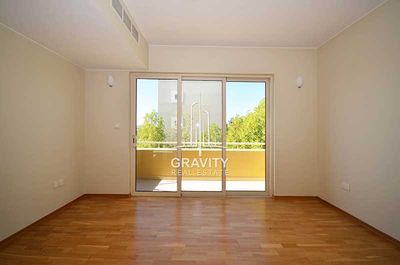 Huge-bedroom-having-wooden-floorings-and-sliding-windowed-doors-opening-to-a-balcony-in-al-raha-gardens