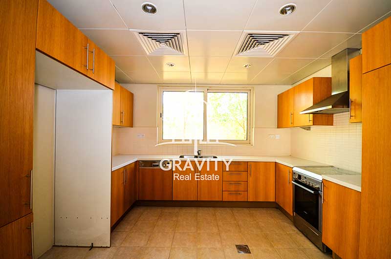 Immense-kitchen-space-with-a-window-wooden-cabinets-and-drawers-built-exhaust-and-stove-and-open-space-for-appliances-in-Al-Raha-Gardens