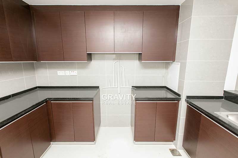 Kitchen-having-space-for-stove-wooden-cabinets-and-marbeled-tabletops-in-burooj-views