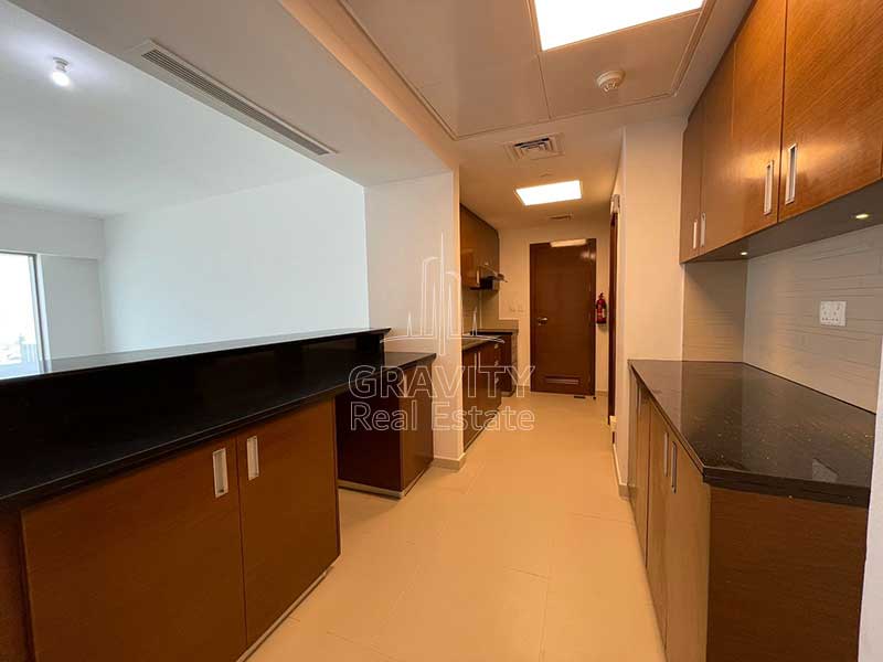 Long-kitchen-with-wooden-cabinets-in-2-bedroom-apartment-in-al-reem-island