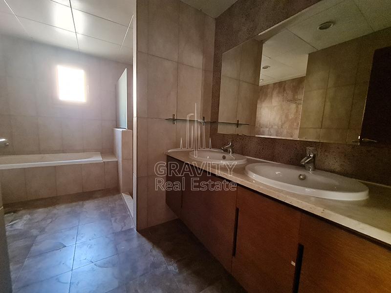 Master-toilet-in-the-4-bedroom-Villa-in-Al-Raha-Gardens-that-has-two-sinks-wooden-cabinets-a-bathtub-and-a-separate-partition-for-shower