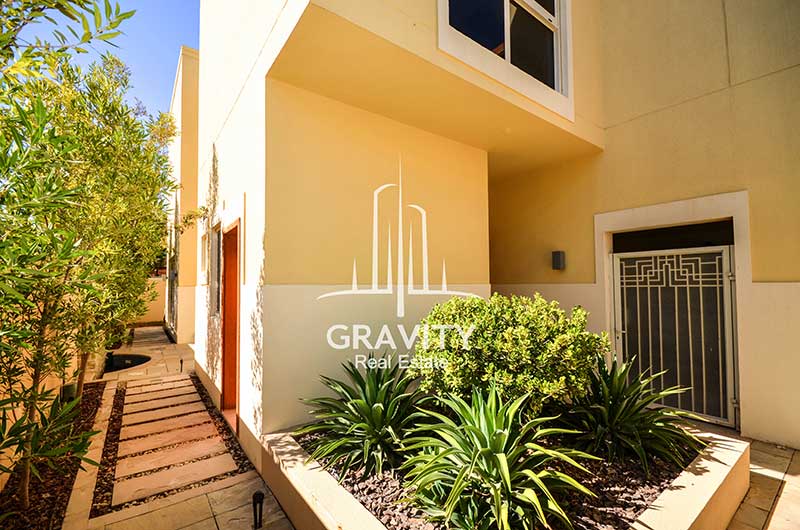 Narrow-tiled-pathway-with-small-trees-to-the-back-of-a-Townhouse-in-Al-Raha-Gardens