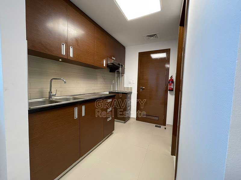 Open-kitchen-gate-tower-1-abu-dhabi-having-wooden-cabinets-and-a-door-to-store-room