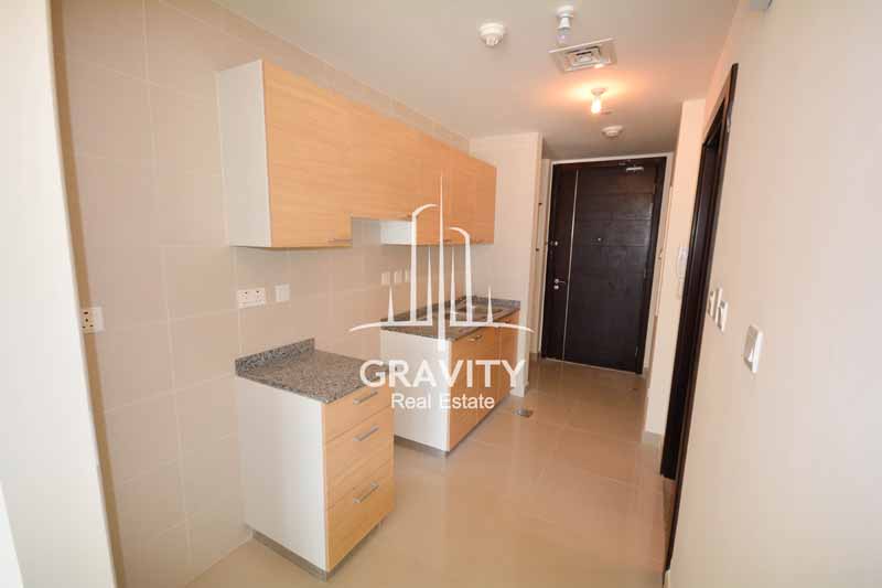 spacious-open-kitchen-with-light-brown-wooden-cabinets-in-nice-studio-apartment-in-sigma-tower-reem-island