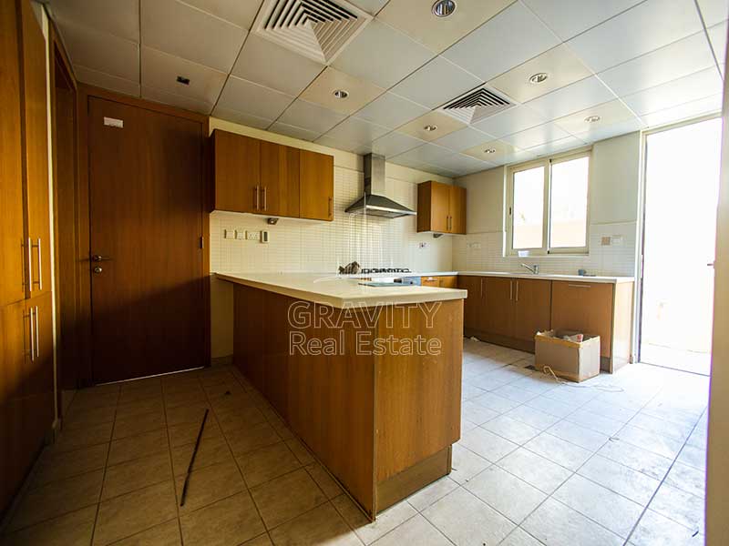 pacious-Kitchen-with-wooden-cabinets-and-shelves-tabletop-counter-exhaust-and-window-in-Al-Raha-Garden