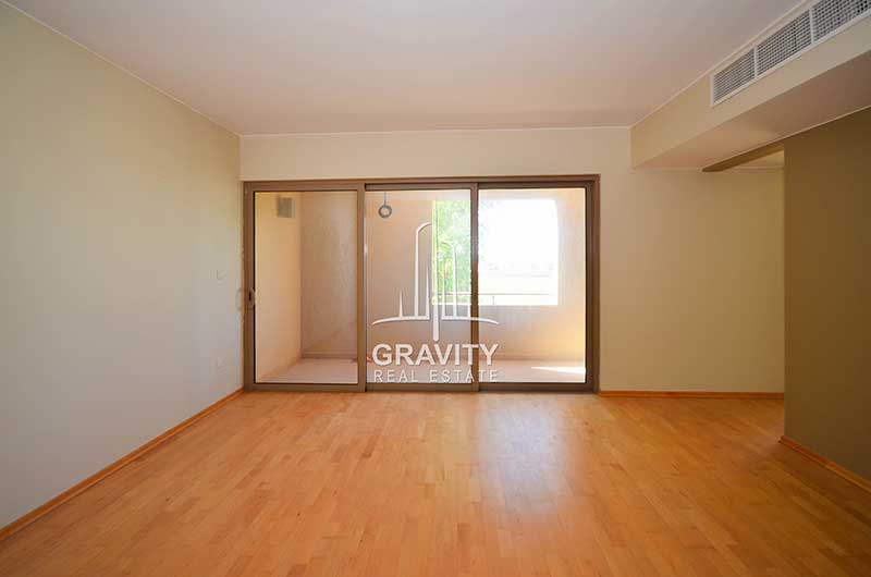 Spacious-room-with-white-walls-brown-wooden-floorings-opening-to-the-right-side-and-windowed-sliding-doors-opening