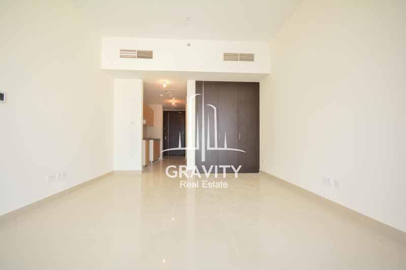 living-area-with-brown-built-in-wardrobe-and-kitchen-with-light-brown-cabinets-in-studio-apartment-in-sigma-tower-reem-island