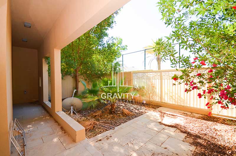 The-backyard-of-a-3-bedroom-Townhouse-in-Al-Raha-Garden-has-trees-dry-leaves-on-the-floor-and-a-mini-satellite