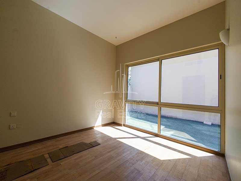 The-bedroom-in-the-Al-Raha-Garden-house-has-a-wooden-floor-and-a-large-window