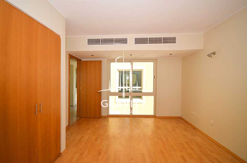 bedroom-in-Al-Raha-Garden-Townhouse-has-wooden-floorings-and-fitted-wooden-wardrobe-on-the-left-side-and-a-window