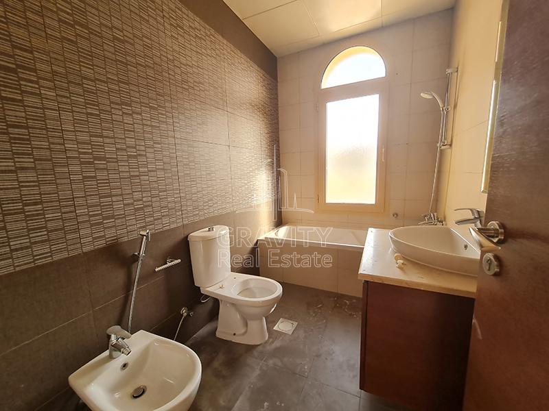 fancy-artistic-brown-tiles-on-the-walls-of-a-toilet-in-the-Al-Raha-Golf-Gardens-villa-that-has-a-bathtub