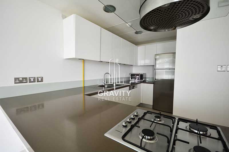 kitchen-in-al-raha-apartment-with-white-cabinets-running-to-the-sides-a-wash-basin-and-cooking-unit