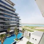 yas-island-mayan-balcony-with-pool-and-canal-view-with-palms-on-the-side-of-the-pool-and-buliding-facing-the-balcony