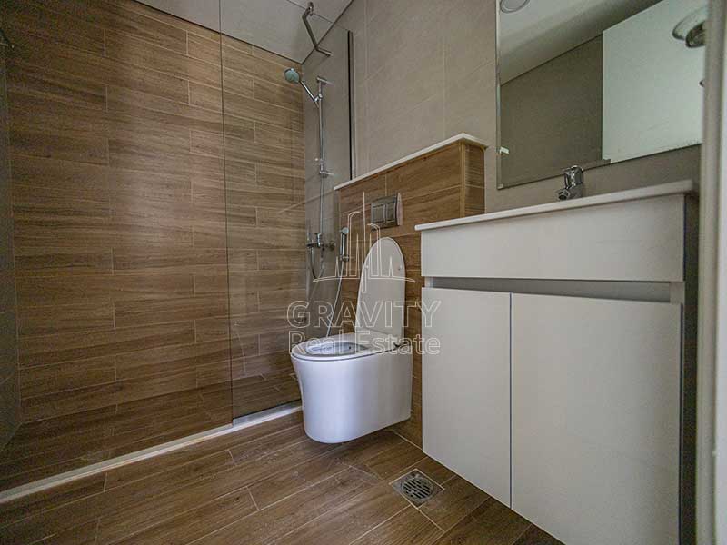 bathroom-with-wooden-floors-cabinets-sink-and-toilet-in-1-bedroom-apartment-in-al-raha-beach