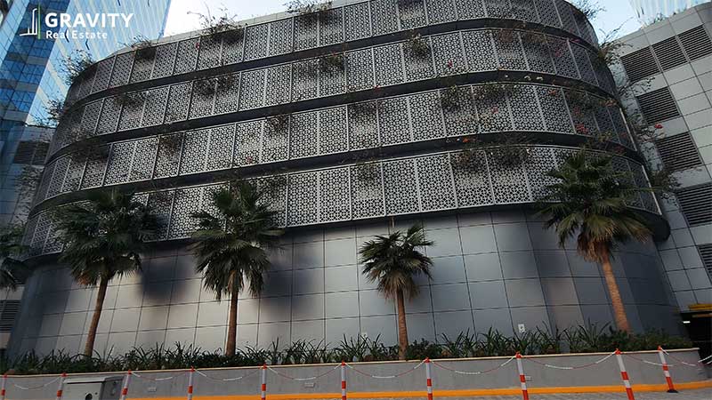 bottom-up-view-of-Marina-Bays-exterior-cladding-with-greenery-and-flowers-poking-out-of-the-cladding-and-palm-trees-at-the-complexes-feet