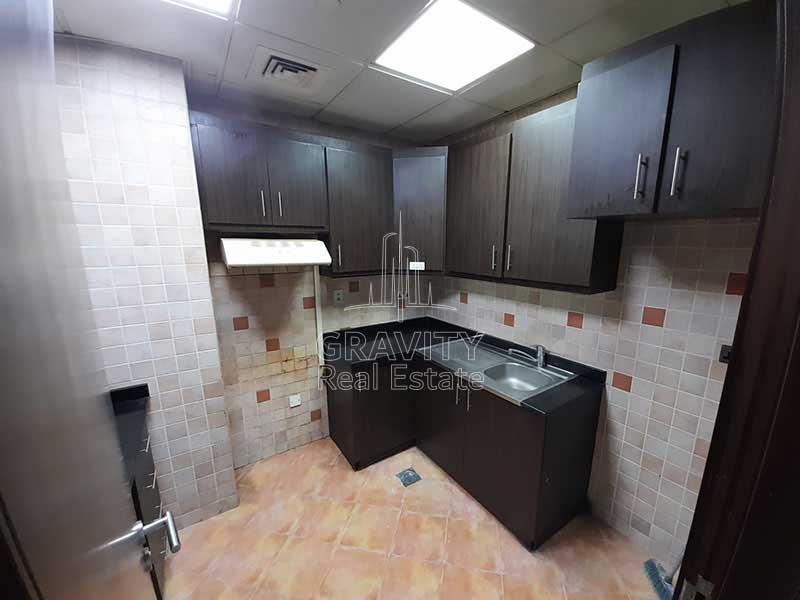 open-kitchen-with-brown-rectangular-wooden-cabinets-and-colorful-tiles-in-apartment-in-hydra-avenue-towers