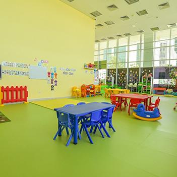 spacious-interior-of-playhouse-nursery-with-colorful-plastic-chairs-for-children-pictures-glued-to-walls-and-toys-on-the-ground