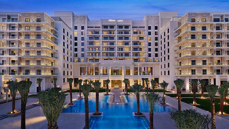 Hilton-hotel-yas-island-outdoor-courtyard-with-young-date-palms-enveloped-by-body-of-water