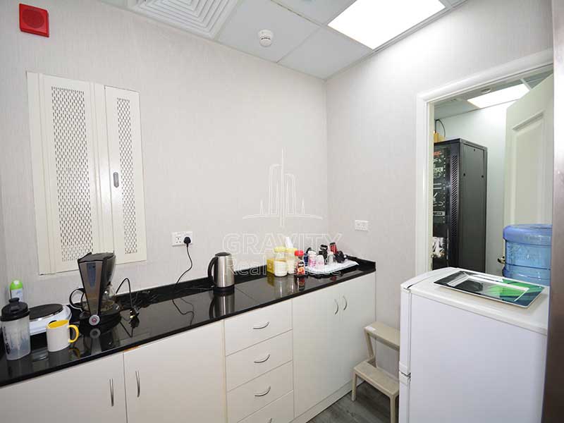 Clean-white-wet-pantry-with-black-tiles-on-top-with-a-fridge-in-addax-tower