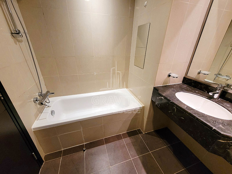 bathroom-with-white-bathtub-and-dark-brown-ceramic-tiles-in-2-bedroom-apartment-in-sky-tower