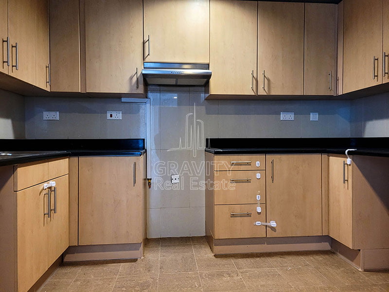 closed-kitchen-with-beige-cabinets-and-light-brown-ceramic-tiles-in-2-bedroom-apartment-in-sky-tower