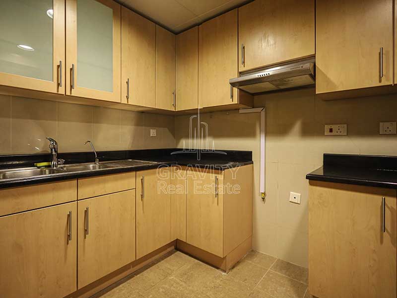 closed-kitchen-with-light-brown-cabinets-and-light-brown-tiles-in-1-bedroom-apartment-in-sky-tower-reem-island