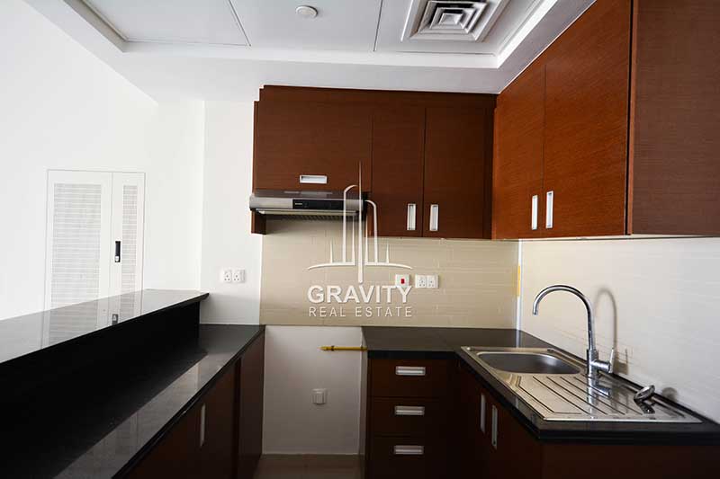 open-kitchen-with-brown-cabinets-black-counter-top-in-a-1-bedroom-apartment-in-the-arc-tower-reem-island