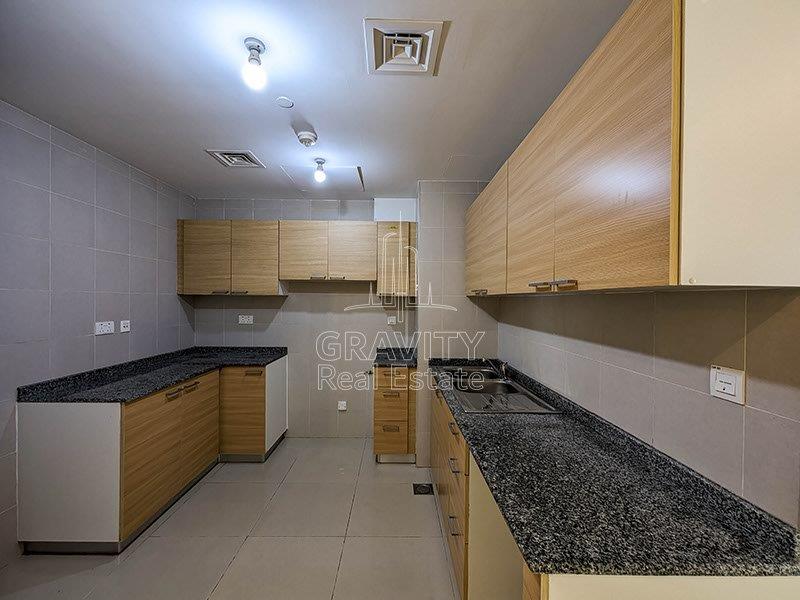 open-kitchen-with-light-colored-cabinets-and-black-marbled-counter-top-in-a-3-br-apt-in-marina-bay-reem-island