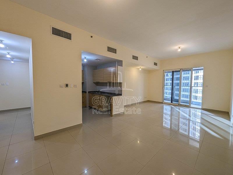 spacious-living-area-with-attached-open-kitchen-and-wide-glass-panel-window-in-3-br-apartment-in-marina-bay-reem-island