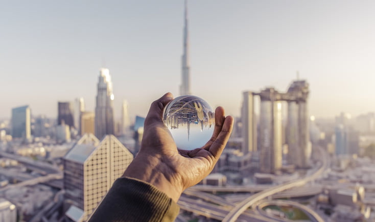 clear-crystal-ball-held-by-hand-with-dubai-skyline-in-the-background