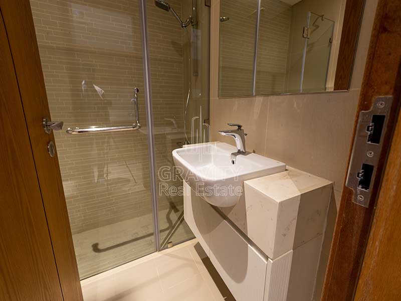 bathroom-with-white-sink-and-shower-area-in-studio-apartment-in-julphar-residence-abu-dhabi