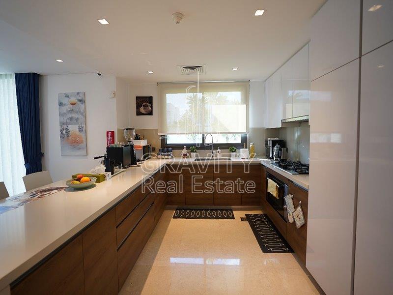 modern-kitchen-with-appliaces-brown-cabinets-white-marbled-counter-tops-in-aspens-yas-acres-duplex-4br-apt