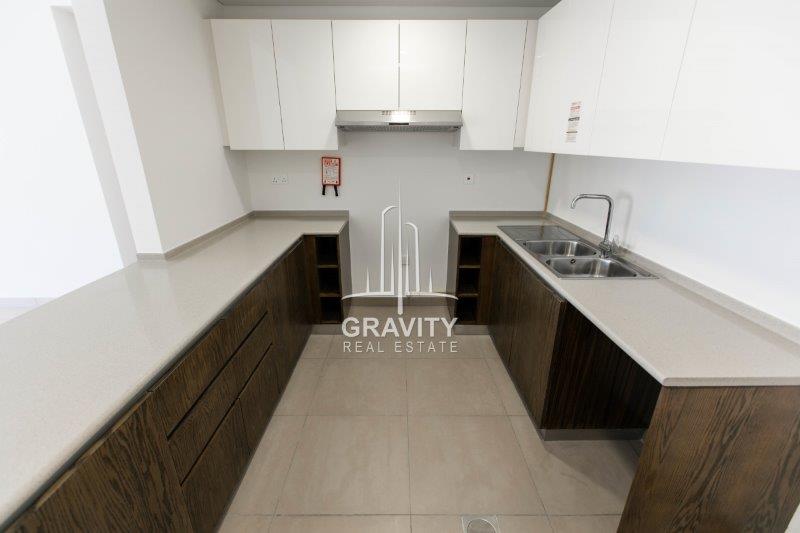 open-kitchen-w-marbled-counter-brown-cabinets-and-white-cupboard--in-a-2-BR-apt-in-the-wave-tower-reem-isl