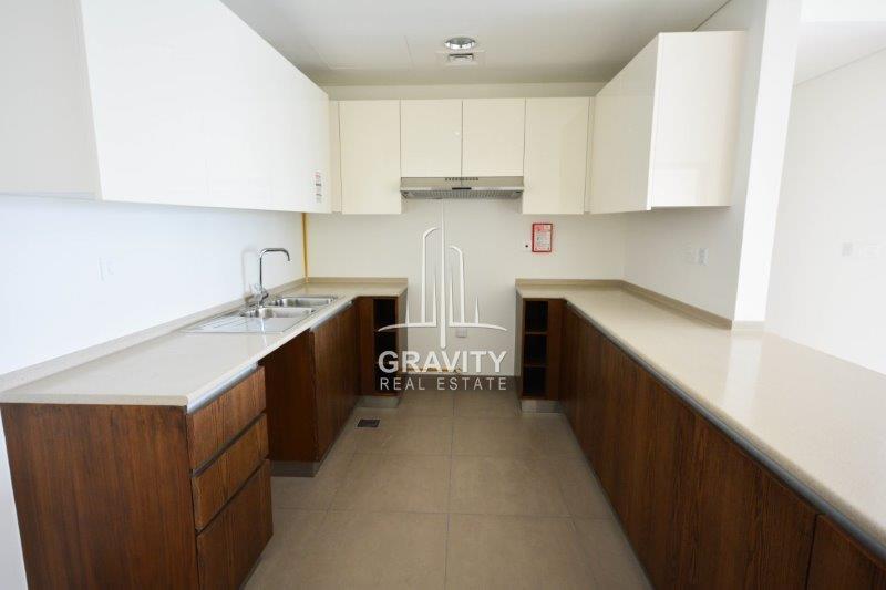 open-kitchen-with-marbled-counter-brown-cabinets-and-white-cupboard--in-a-3-BR-apt-in-the-wave-abu-dhabi