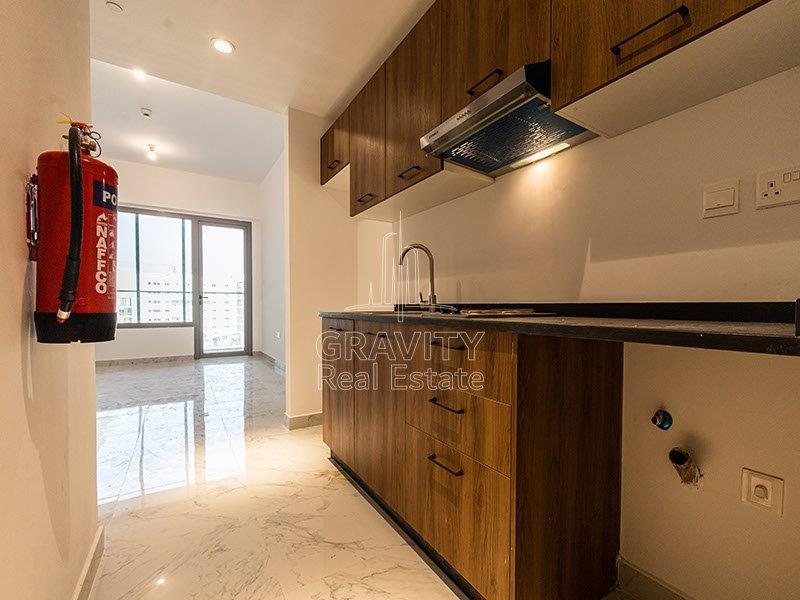 open-kitchen-with-wooden-touched-cupboards-and-a-fire-extinguisher-attached-to-the-kitchen-wall-oasis-residences