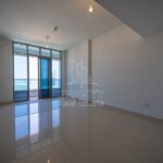 spacious-living-room-with-huge-blue-tinted-glass-door-leading-to-balcony-in-apartment-in-julphar-residence