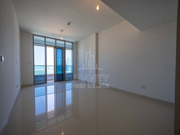 spacious-living-room-with-huge-blue-tinted-glass-door-leading-to-balcony-in-apartment-in-julphar-residence