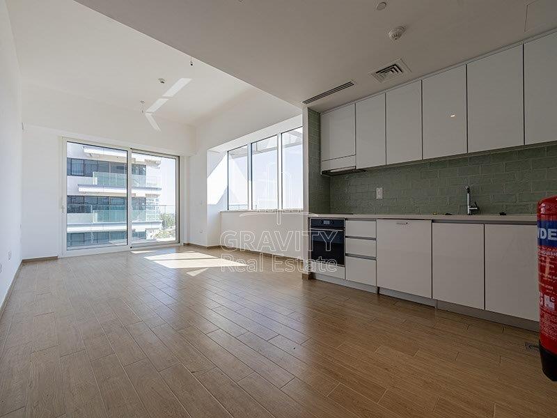 spacious-studio-area-with-wooden-touched-floor-and-window-panels-letting-sun-rays-inside-in-mayan-apartments