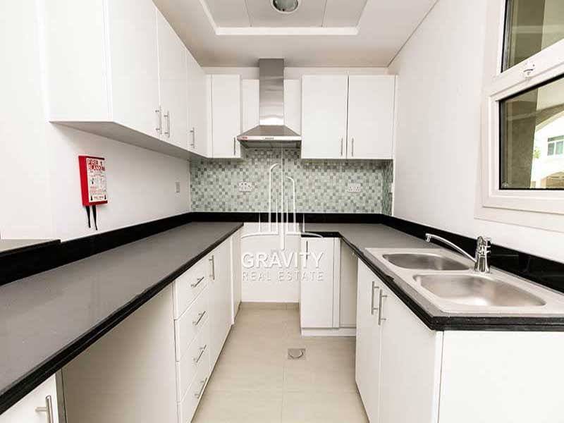 al-ghadeer-abu-dhabi-property-kitchen-with-marble-counter-top-and-white-cabinets-and-steel-sink