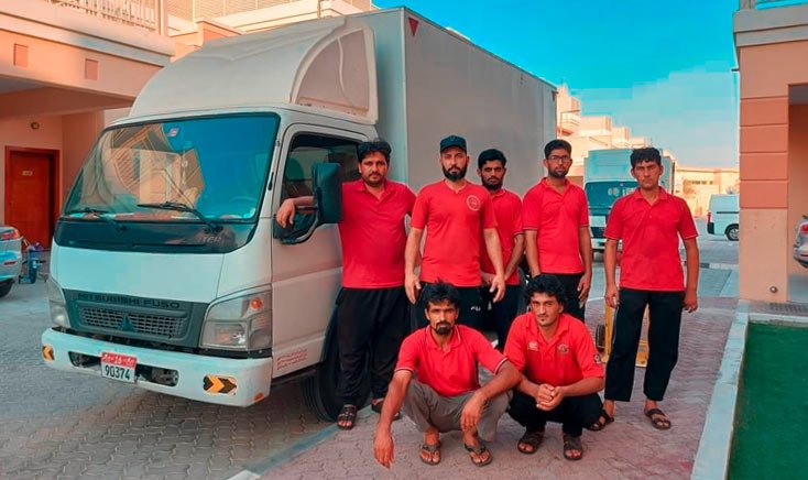 Ezee-movers-and-packers-in-abu-dhabi-team-in-red-uniform-standing-near-a-mini-truck