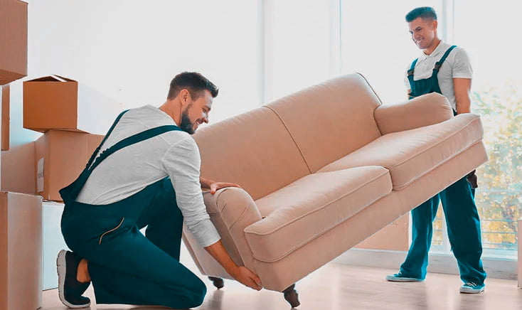 two-movers-in-overalls-moving-a-two-seat-sofa-together