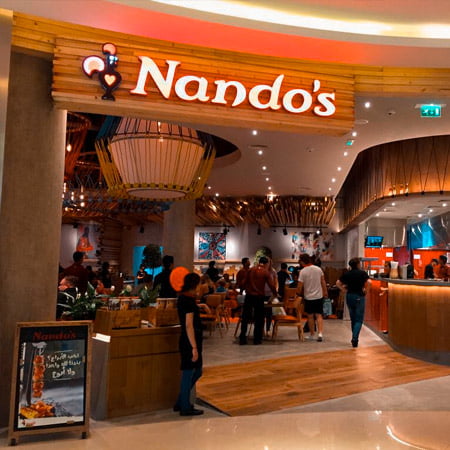 Customers eating inside Nandos restaurant near Al Zeina