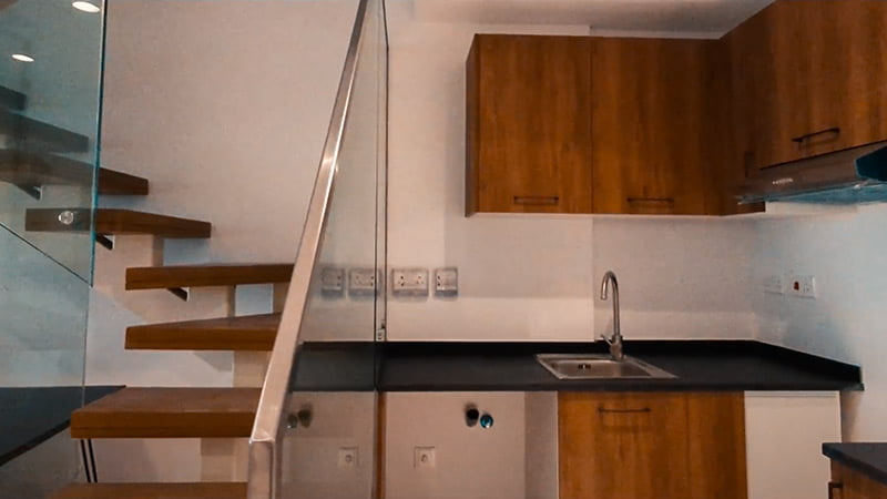 wooden kitchen cabinet beside wooden stairs with glass railings