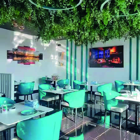 green chairs and white table with plants ceiling inside a restaurant